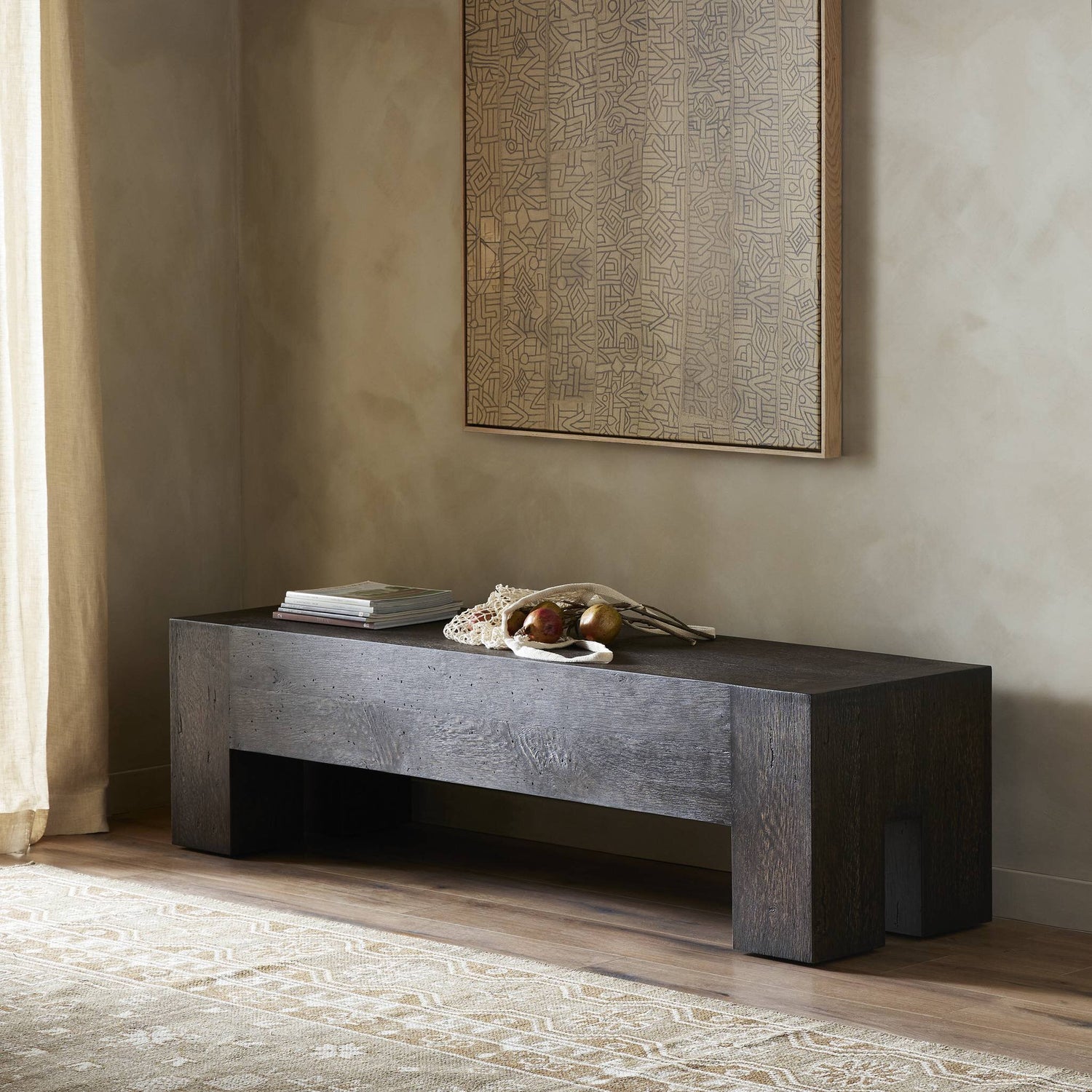 Rustic oak veneer accent bench with chunky squared legs and dovetail joinery, displayed in a minimalist interior setting with neutral tones, wall art, and decorative objects on top.